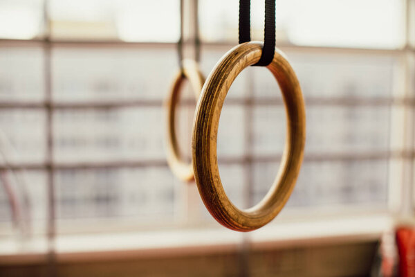 Detail of a set of rings, or steady rings, in a gymnasium over a white wall with copy space in a healthy lifestyle and fitness concept