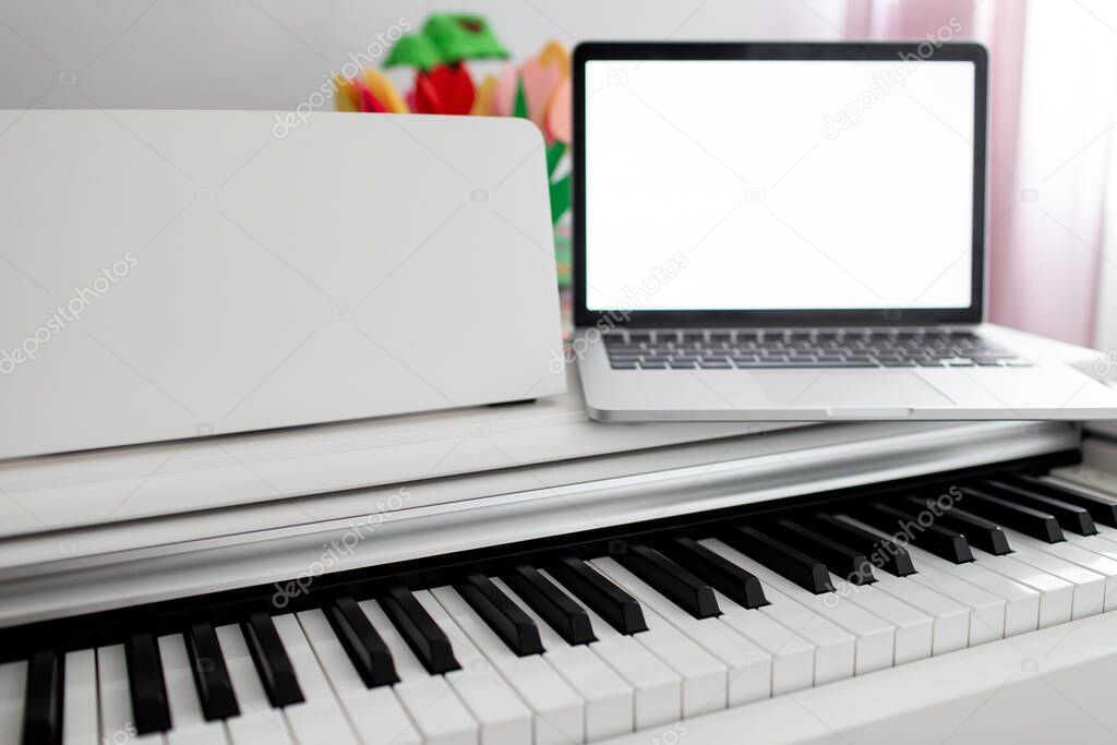 a white piano with a laptop on it. remote training, online education