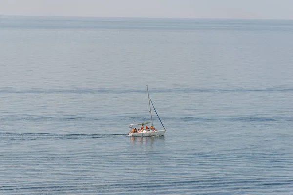 Flygfoto på en vit flytande segelbåt med människor i det blå svarta havet — Stockfoto