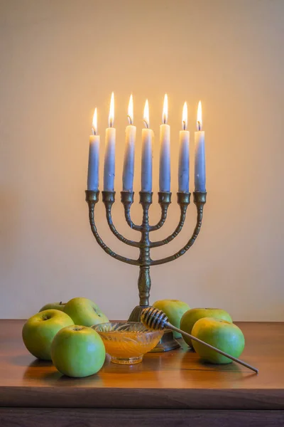 Traditionell judisk menorah med brinnande ljus, äpplen och en glasskål med honung för firandet av Hanukkah — Stockfoto