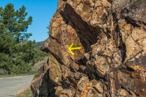 Bir kayaya boyanmış sarı ok. Saint James Yolu 'ndaki hacılar için yön işareti (Camino de Santiago) Galiçya, İspanya