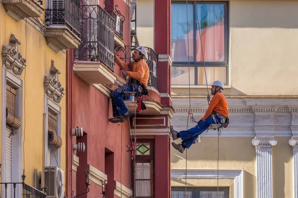 Seville, İspanya, 2 Mayıs 2017. Endüstriyel tırmanışçılar evin ön cephesini turuncuya boyuyorlar..