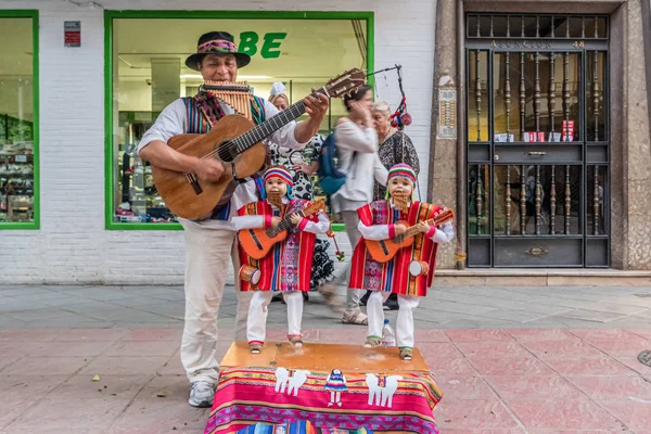 Seville, İspanya, Mayıs 3, 2017. Dans eden bebekleriyle Perulu bir Hintli Sevilla Fuarı sırasında sokakta flüt, gitar ve şıngırtı çalıyor..