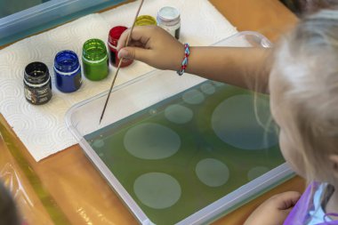 Ebru resmi. Hayatında ilk kez, küçük bir kız suyun üzerine resim çizer (ebru). Resim 1.