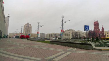 Açılış fenerleri ve kırmızı tuğlalı katolik katedrali ve basit ofis binaları olan büyük kırmızı bayraklarla döşenmiş büyük bir şehir meydanı.