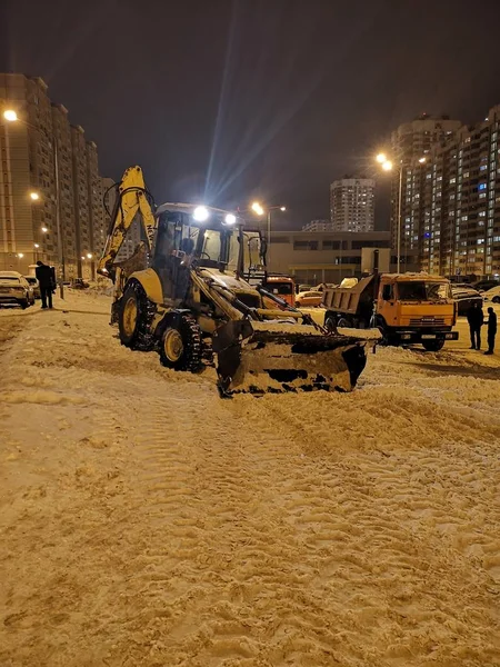 Bir Buldozer Gece Fenerlerin Işığında Yüksek Evlerin Yakınında Karla Kaplı — Stok fotoğraf