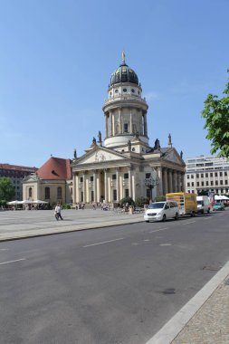 Mavi gökyüzüne karşı caddenin karşı tarafında kubbesi ve sütunları olan eski bir taş binanın görüntüsü