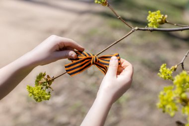 Saint George's ribbon in the hands of a child. Concept of national holidays in Russia: remembrance day, 9 may, Russia day clipart