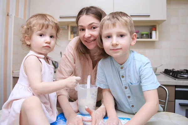 happy mom cooks pizza with her kids at home, lifestyle