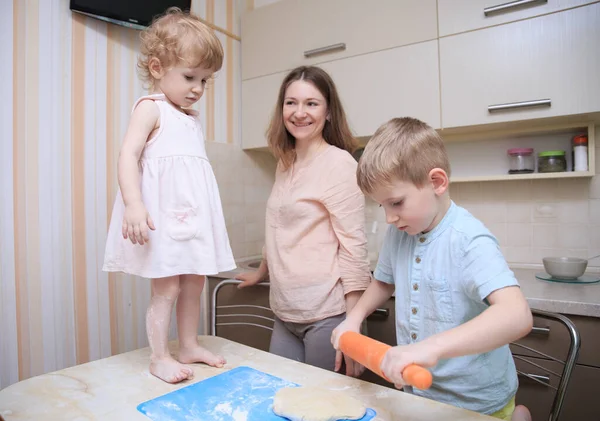 happy mom cooks pizza with her kids at home, lifestyle