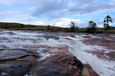 river flowing on red jasper in gran sabana clipart