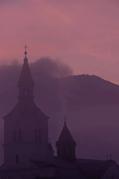 Church covered in mist with sunlit cloud
