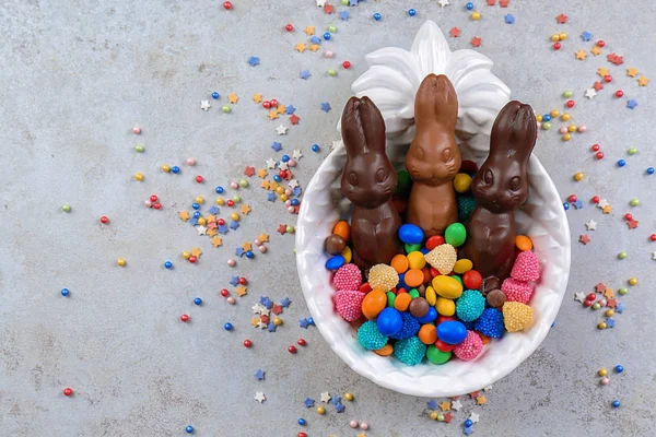 Plato con conejitos de Pascua de chocolate y caramelos en la mesa, vista superior — Foto de Stock