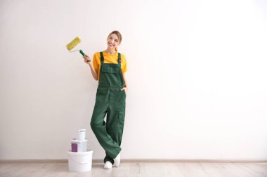 Boş odada boya silindiri ile genç kadın dekoratör