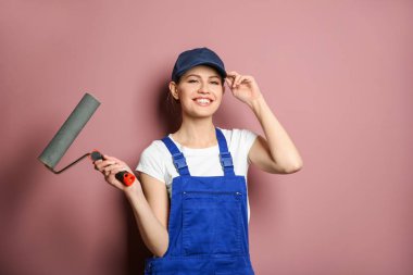 Renk duvarının yakınında boya silindiri ile genç kadın dekoratör