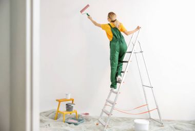 Boş odada genç kadın dekoratör boyama duvar