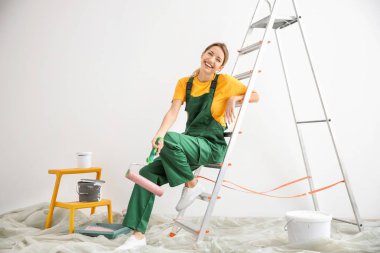 Boş odada boya silindiri ile genç kadın dekoratör