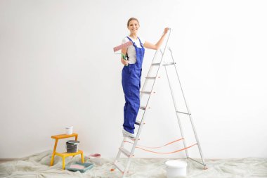 Boş odada boya silindiri ile genç kadın dekoratör