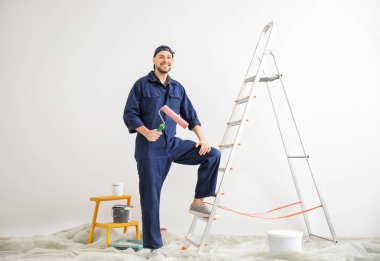 Boş odada boya silindiri ile genç erkek dekoratör