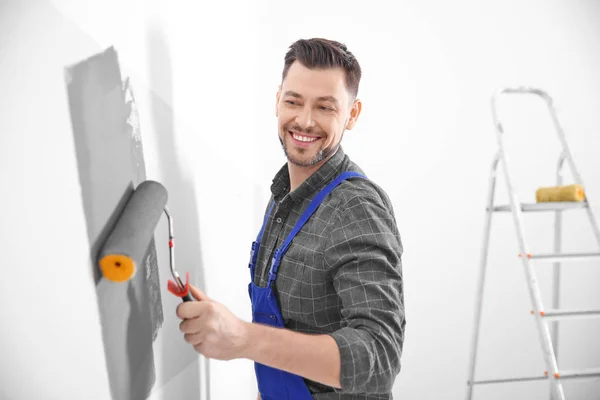 Jovem macho decorador parede de pintura no quarto — Fotografia de Stock