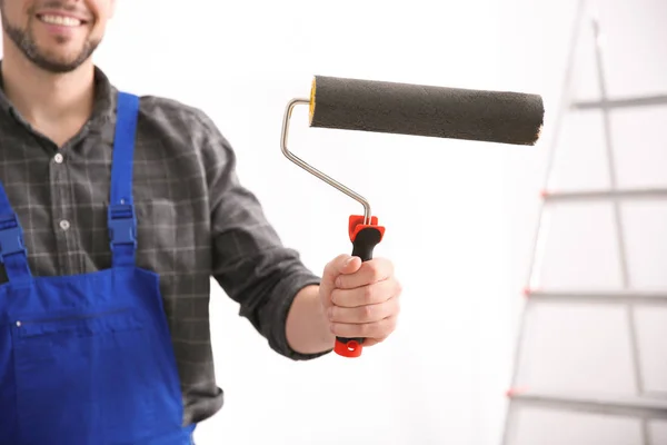 Jovem decorador com rolo de pintura no quarto — Fotografia de Stock