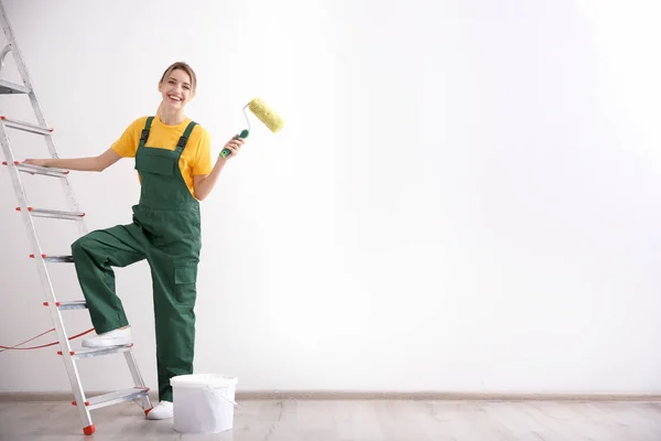 Unga kvinnliga dekoratör med paint roller i tomma rum — Stockfoto