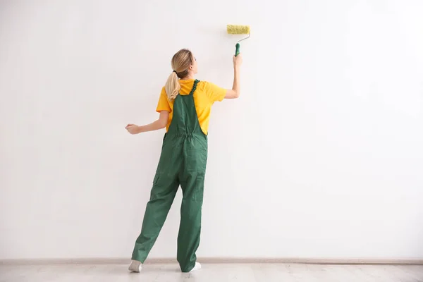 Joven decoradora pintando pared en habitación vacía — Foto de Stock