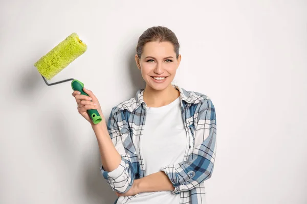 Jovem decorador feminino com rolo de pintura no fundo branco — Fotografia de Stock