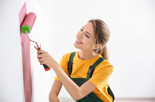 Young female decorator painting wall in room — Stock Photo, Image