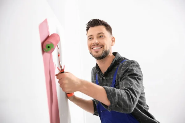 Jovem macho decorador parede de pintura no quarto — Fotografia de Stock