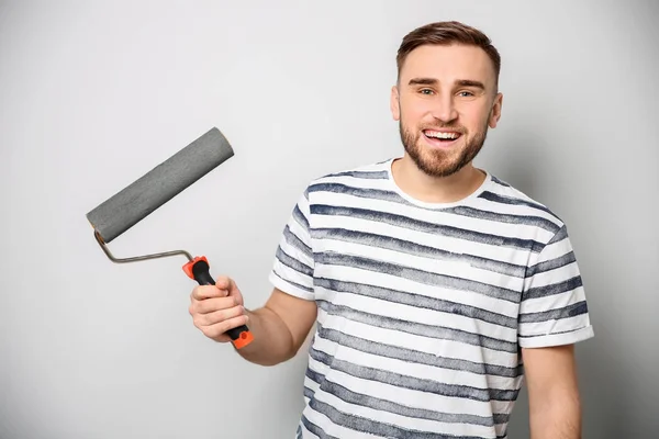 Young male decorator with paint roller on white background — Stock Photo, Image