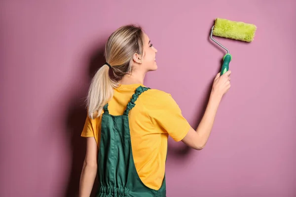 Decoración femenina joven con rodillo de pintura cerca de la pared de color — Foto de Stock