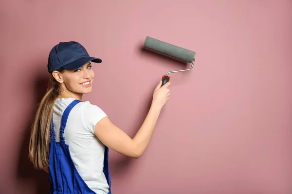 Jovem decorador feminino com rolo de pintura perto da parede de cor — Fotografia de Stock