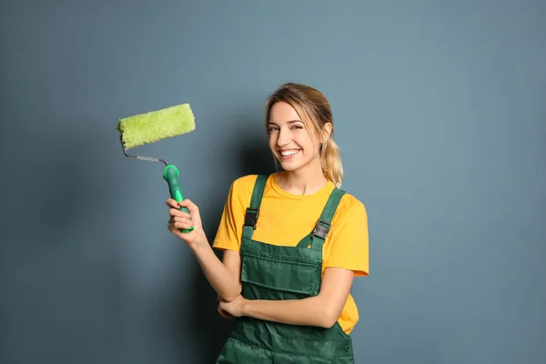 Jonge vrouwelijke decorateur met verfroller in de buurt van kleur muur — Stockfoto