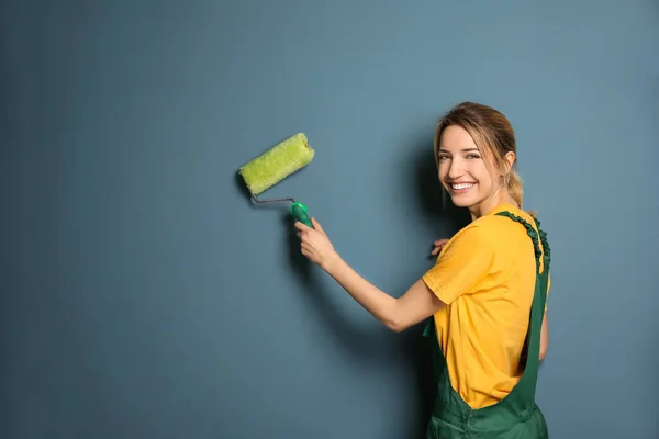 Decoración femenina joven con rodillo de pintura cerca de la pared de color — Foto de Stock