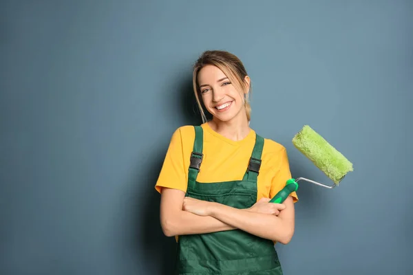 Young female decorator with paint roller near color wall — Stock Photo, Image