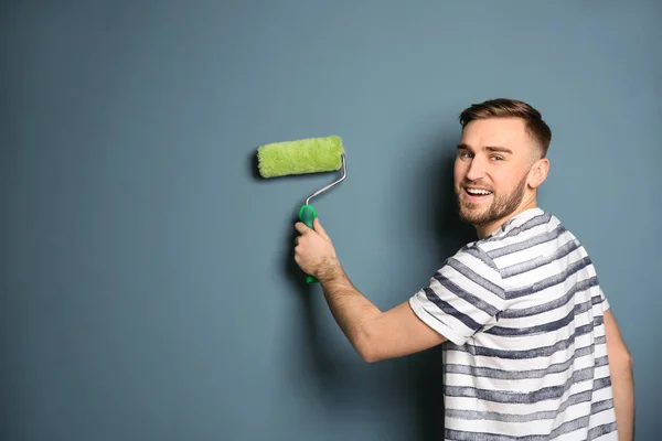 Jeune décorateur masculin avec rouleau de peinture près du mur de couleur — Photo
