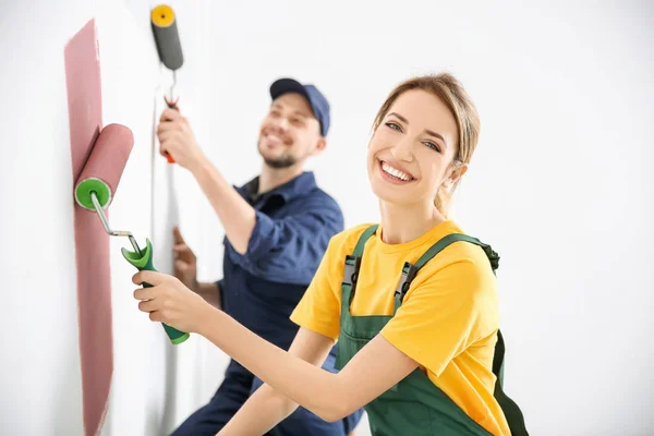 Jóvenes decoradores pintando pared en habitación — Foto de Stock