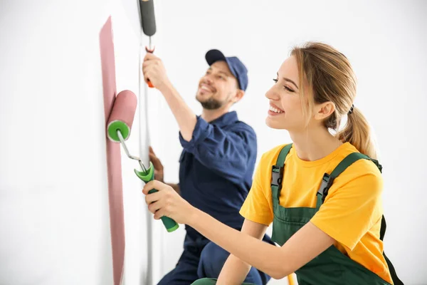 Jóvenes decoradores pintando pared en habitación — Foto de Stock