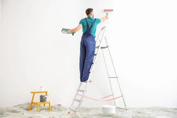 Jonge mannelijke decorateur schilderen muur in lege ruimte — Stockfoto