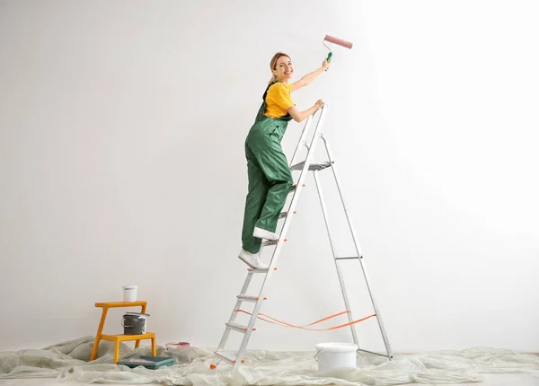 Unga kvinnliga dekoratör målning vägg i tomma rum — Stockfoto