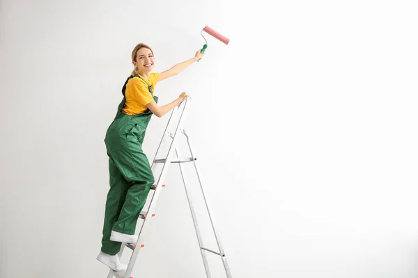 Joven decoradora pintando pared en habitación vacía — Foto de Stock