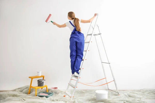 Mladá žena dekoratér Malování zdi v prázdné místnosti — Stock fotografie