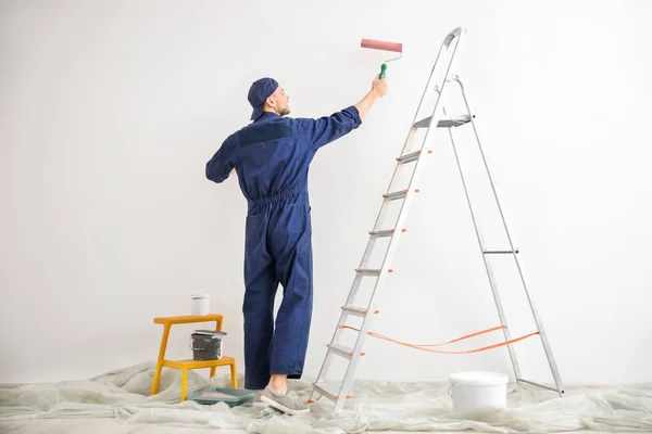 Молодий чоловічий декоратор малює стіну в порожній кімнаті — стокове фото