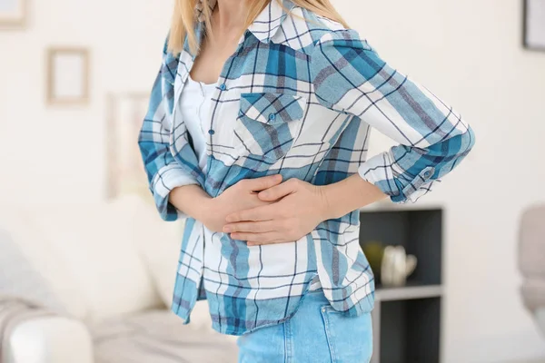 Mladá žena trpící bolestí žaludku doma — Stock fotografie