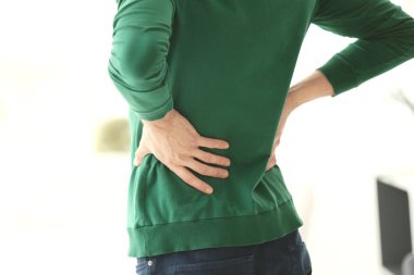 Evde sırt ağrısı çeken genç bir adam.