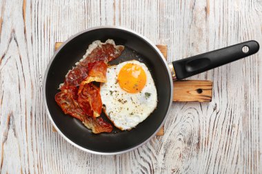 Tavada kızarmış yumurta ve domuz pastırması ahşap arka plan üzerinde