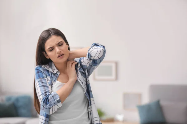 Młoda kobieta cierpi na ból szyi w domu — Zdjęcie stockowe