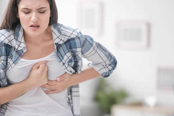 Young woman suffering from chest pain at home