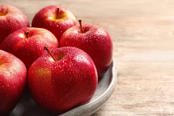 Assiette avec pommes rouges mûres sur fond en bois — Photo